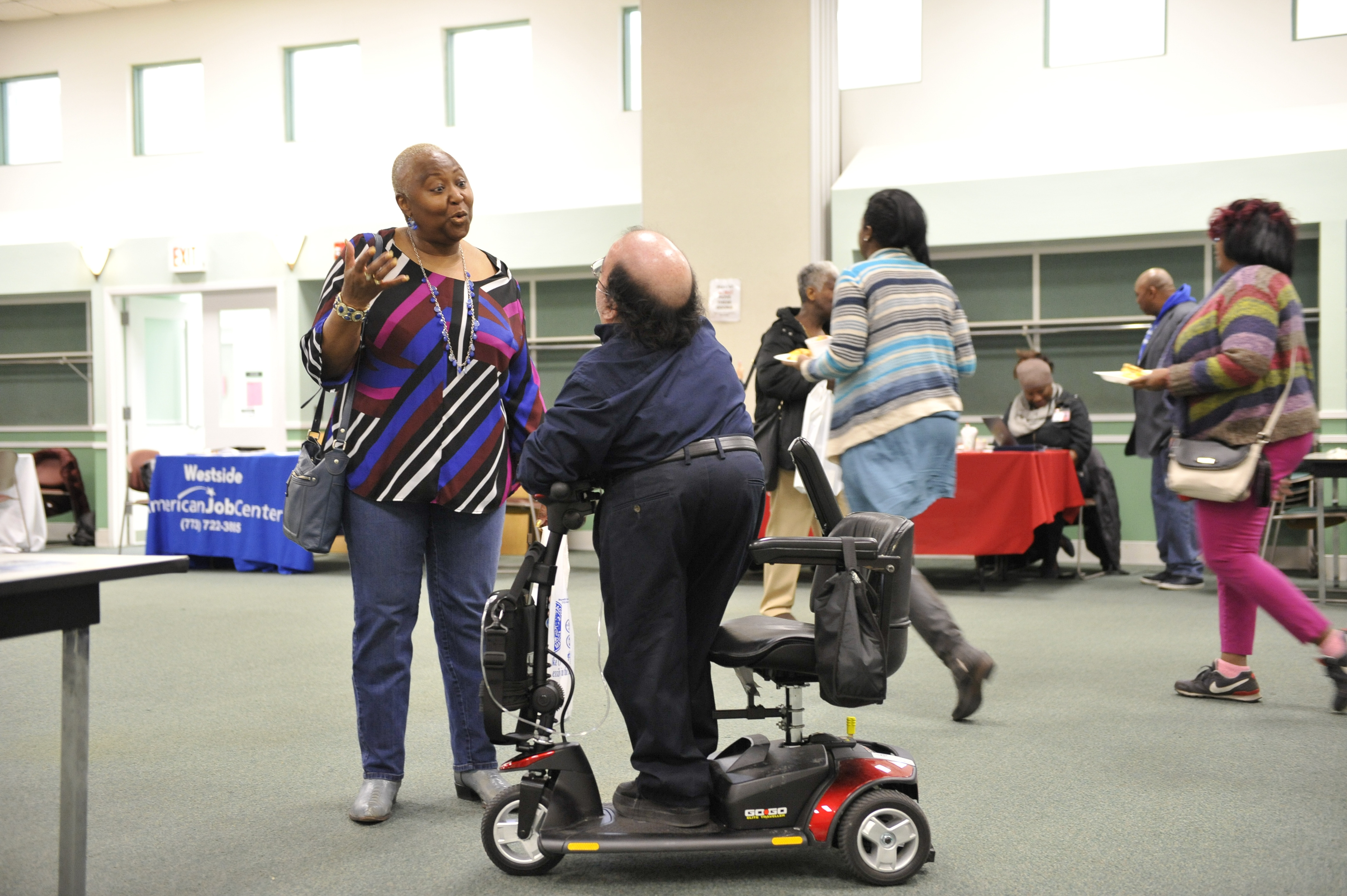 Youth Transition event an a woman standing speaking with a gentleman standing on a scooter Youth Transition event an a woman standing speaking with a gentleman standing on a scooter